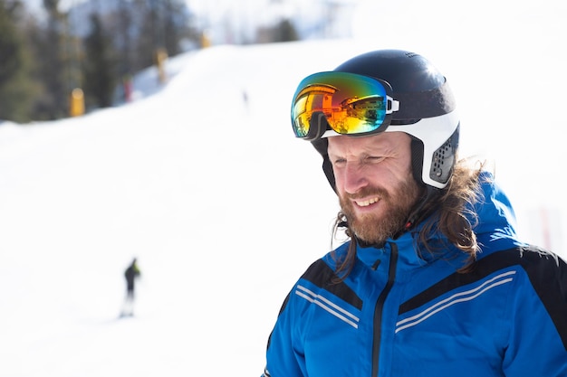 Esquiador feliz e sorridente homem com roupas azuis em uma encosta com montanhas ao fundo na área de resort de esqui de Cortina d'Ampezzo Faloria Dolomiti Itália