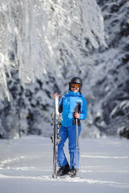 Esquiador femenina de pie disfrutando de un día soleado contra hermosos árboles cubiertos de nieve en el fondo