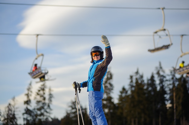 Esquiador feminino contra ski-lift e floresta em um dia ensolarado