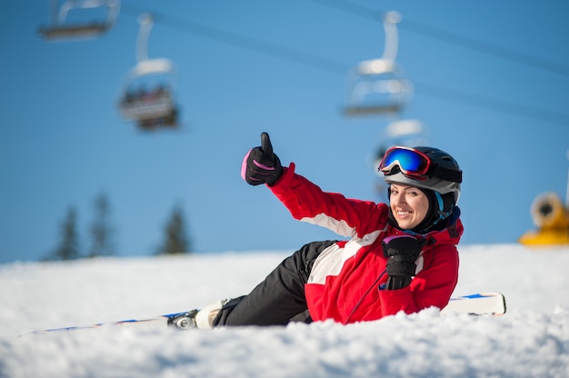 Esquiador feminino deitado com esquis na neve no topo da montanha