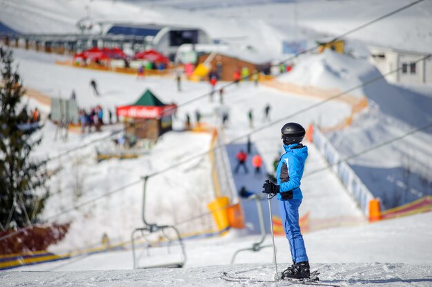 Foto esquiador feminino em pé em uma pista de esqui em um dia ensolarado