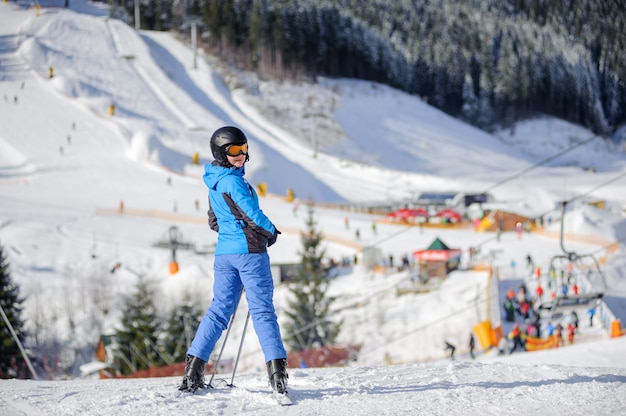 Esquiador feminino em uma pista de esqui em um dia ensolarado