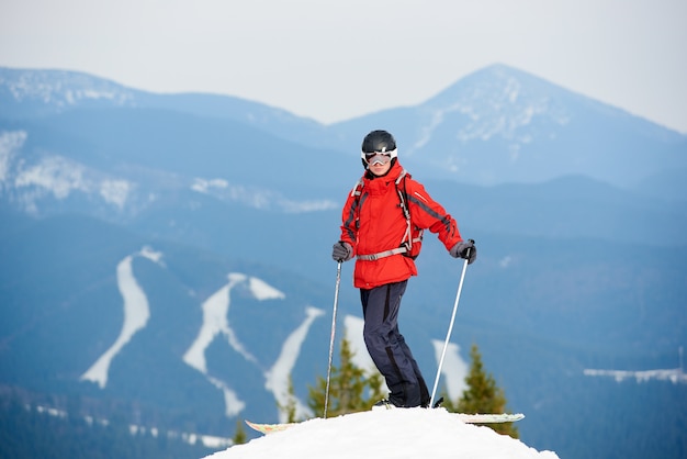 Esquiador masculino em pé no topo da encosta na estância de esqui de inverno