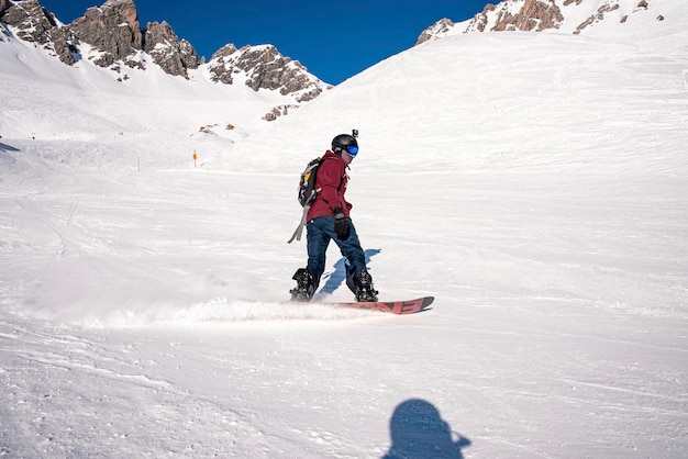 Esquiador masculino esquiando na montanha de neve durante o dia ensolarado