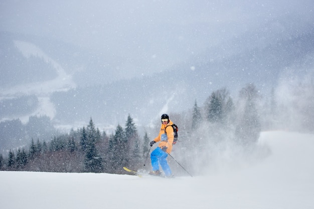 Esquiador posando de pie sobre esquís en polvo de nieve profunda en nevadas densas en las montañas