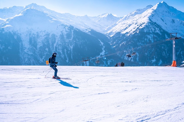Esquiador en ropa deportiva esquiando en la montaña contra el remonte en clima frío