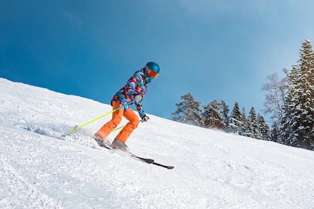 Una esquiadora baja por la pendiente en un día soleado en un resort de montaña