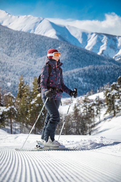Foto esquiadora disfrutando de la vista de las montañas en la ladera de terciopelo en un día soleado en una estación de esquí