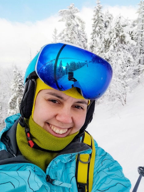 Esquiadora sorridente tirando foto de uma selfie na temporada de inverno