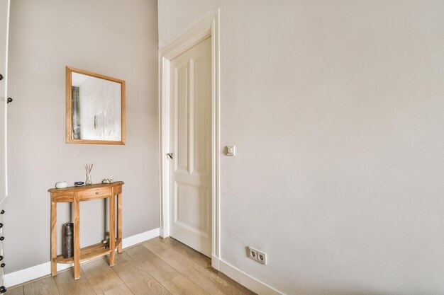 Esquina de la habitación blanca con espejo de puerta y mesita