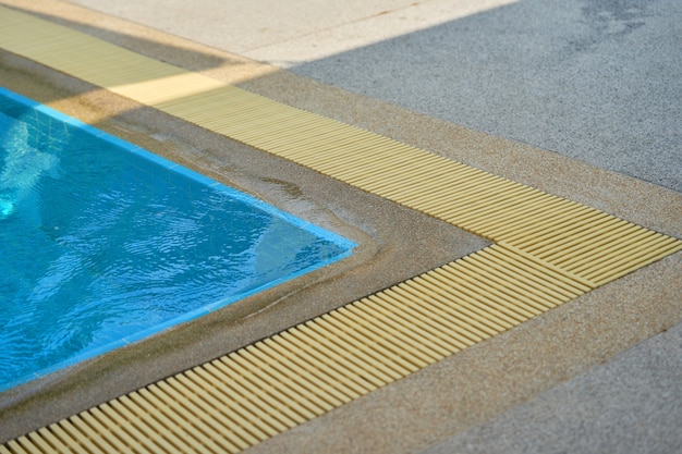 Esquina de la piscina con rejilla de drenaje de agua con sombra