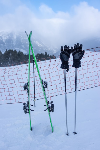 Esquis e bastões com luvas pregadas na neve das pistas de esqui nos Pirenéus Andorra