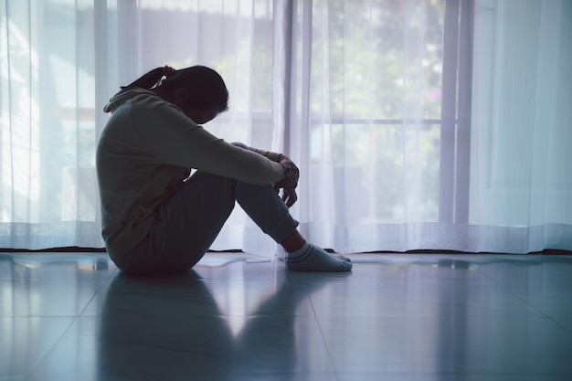 Esquizofrenia com solidão e tristeza no conceito de depressão de saúde mental Mulher deprimida sentada contra o chão em casa com quarto escuro sentindo-se miserável As mulheres estão deprimidas com medo e infelizes
