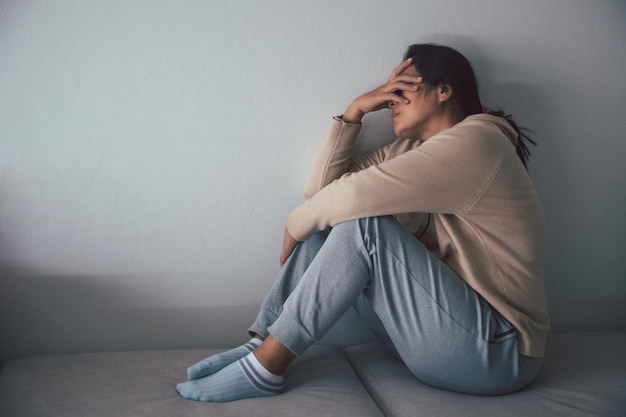 Foto esquizofrenia com solidão e tristeza no conceito de depressão de saúde mental mulher deprimida sentada contra o chão em casa com quarto escuro sentindo-se miserável as mulheres estão deprimidas com medo e infelizes