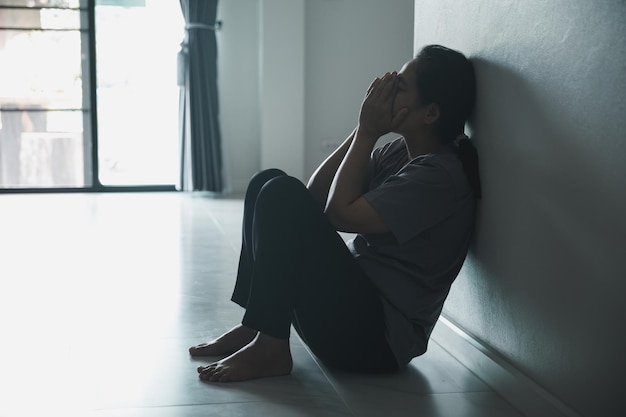 Esquizofrenia con soledad y tristeza en el concepto de depresión de salud mental Mujer deprimida sentada contra la pared en casa con una sombra en la pared sintiéndose miserable Las mujeres están deprimidas temerosas e infelices