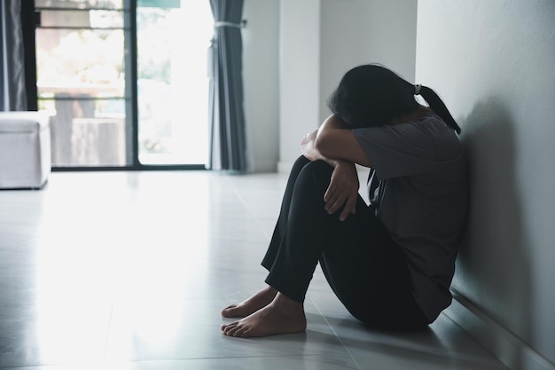 Foto esquizofrenia con soledad y tristeza en el concepto de depresión de salud mental mujer deprimida sentada contra la pared en casa con una sombra en la pared sintiéndose miserable las mujeres están deprimidas temerosas e infelices