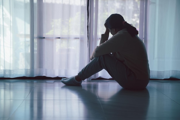 Esquizofrenia con soledad y tristeza en el concepto de depresión de salud mental Mujer deprimida sentada contra el suelo en casa con un cuarto oscuro sintiéndose miserable Las mujeres están deprimidas temerosas e infelices