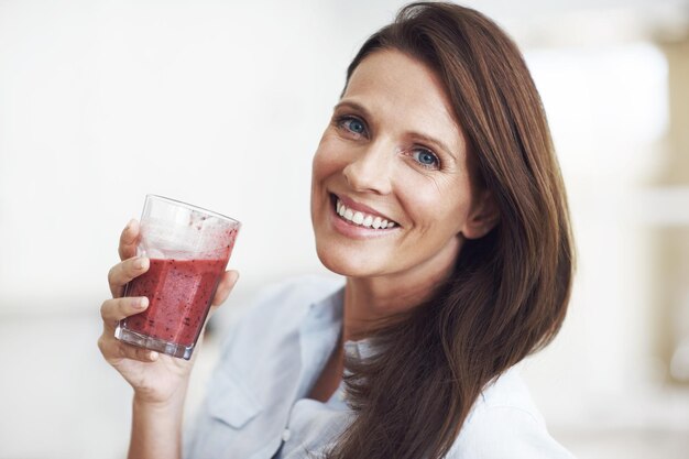 Esse é o seu sorriso de smoothie Captura aproximada de uma mulher atraente desfrutando de um smoothie de frutas