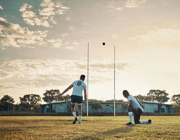 Esse foi um chute de mestre Foto de corpo inteiro de dois jovens jogadores de rugby treinando juntos no campo durante o dia