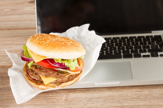 Essen am Arbeitsplatz Fast Food in der Nähe von Laptop-Konzept