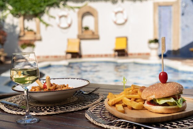 Foto essen am pool. hamburger und nudeln auf holztisch