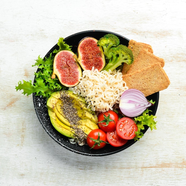 Essen Buddha Bowl Nudeln mit Avocado Feigen Chia und Salat in einer schwarzen Steinplatte Draufsicht Freier Platz für Ihren Text