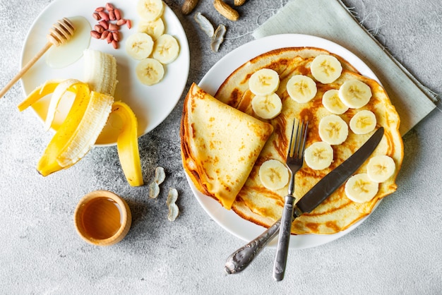 Essen, Dessert, Gebäck, Pfannkuchen, Kuchen. Geschmackvolle schöne Pfannkuchen mit Banane und Honig auf einem konkreten Hintergrund