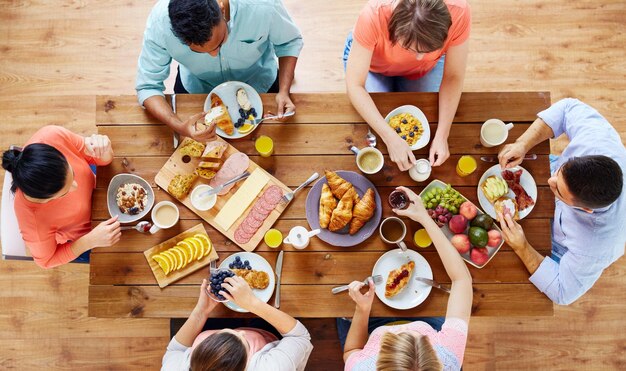 Foto essen essen und familienkonzept gruppe von menschen, die frühstück essen und am tisch sitzen