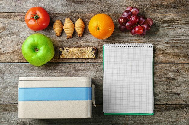 Essen für Schulkinder Brotdose und Notizbuch auf Holzhintergrund