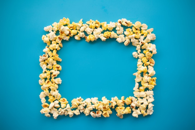 Essen. Gefrorenes Popcorn-Mais-köstliches gelbes Popcorn auf Blau. Kino. Exemplar. Platz für Text