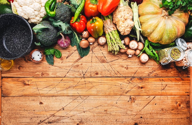 Essen Hintergrund mit veganen Kochzutaten Bio-Gemüse Kürbis Pilze Spargel Paprika Hülsenfrüchte Kichererbsen auf alten Holztisch kopieren