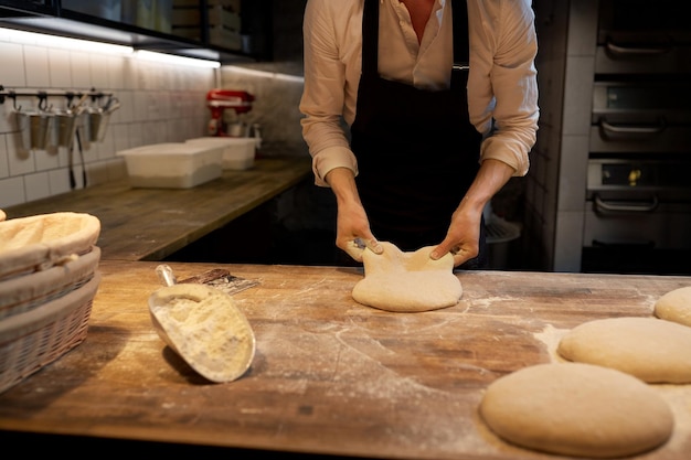 Essen kochen, backen und Menschen Konzept - Koch oder Bäcker portionieren Teig mit Bankschneider in der Bäckerei