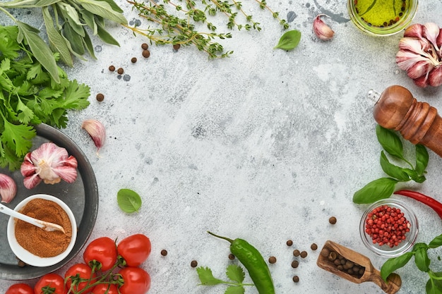 Essen kochen Hintergrund. Frischer Safran, Knoblauch, Koriander, Basilikum, Kirschtomaten, Paprika und Olivenöl, Gewürzkräuter und Gemüse am hellgrauen Schiefertisch. Draufsicht der Lebensmittelzutaten.