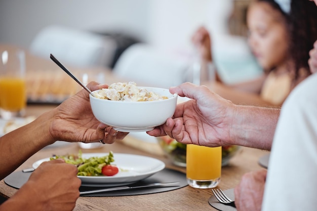 Essen Mittagessen und Hands Pass Schüssel mit köstlicher Pasta zu Hause Brunch Fine Dining und Familie oder Menschen essen und teilen eine leckere Gourmet- und gesunde Mahlzeit auf dem Tisch zusammen im Speisesaal des Hauses