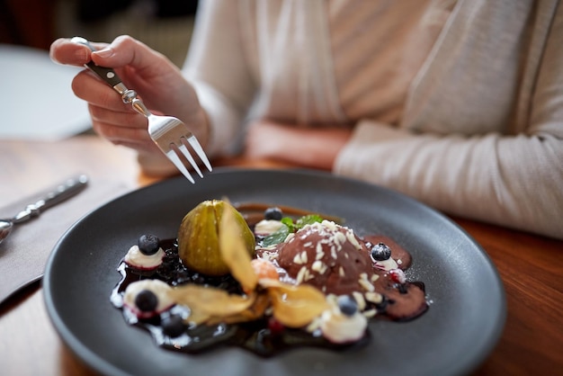 Essen, neue nordische Küche und Menschenkonzept - Frau isst Schokoladen-Eis-Dessert mit Blaubeeren Kissel, Honig gebackener Feige und griechischem Joghurt im Restaurant