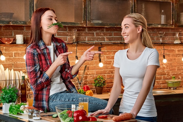 Essen Sie richtig, leben Sie starke junge Freundinnen, die gemeinsam vegetarisches Essen in der modernen Küche gemütlich zubereiten