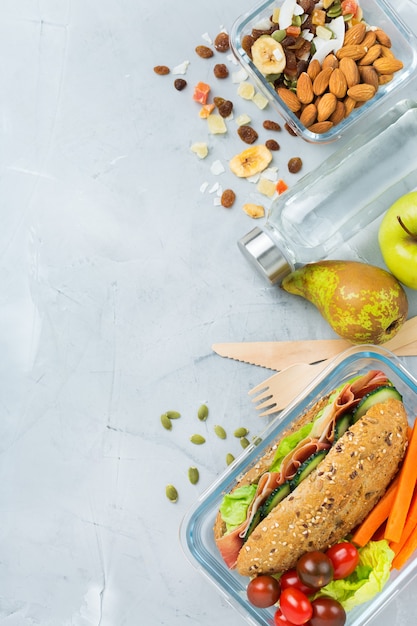 Essen und Trinken, Stillleben, Diät und Ernährung, gesunde Ernährung, Konzept zum Mitnehmen. Lunchbox mit Sandwich, Obst, Gemüse, Nussmischung und einer Flasche Wasser. Draufsicht flach legen, Raumhintergrund kopieren