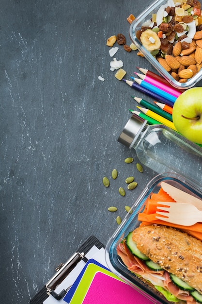 Essen und Trinken, Stillleben, Diät und Ernährung, gesunde Ernährung, Konzept zum Mitnehmen. Schulbrotdose und Schreibwaren. Draufsicht flach legen, Platz Tafelhintergrund kopieren