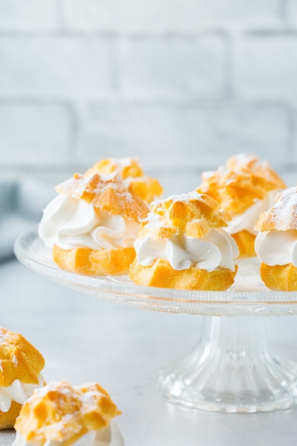 Essen und Trinken, Urlaubskonzept. Köstliche süße hausgemachte Profiteroles mit Sahne auf einem modernen Küchentisch. Raumhintergrund kopieren