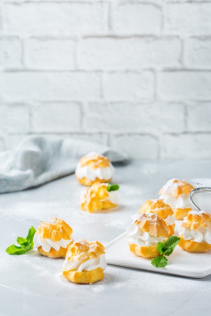 Essen und Trinken, Urlaubskonzept. Köstliche süße hausgemachte Profiteroles mit Sahne auf einem modernen Küchentisch. Raumhintergrund kopieren