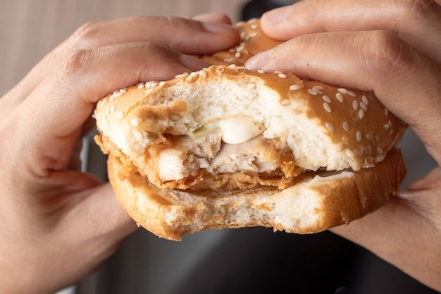 Essen von Käse mit Schweinefleisch-Burger in der Hand in Fast-Food-Restaurant-Junk-Food