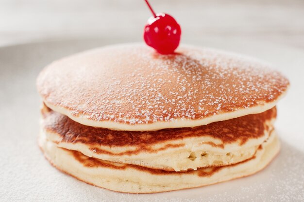 Essen zubereiten. Amerikanische Pfannkuchen mit Kirsche auf weißem Plattenhintergrund. Traditionelles US-Essen.