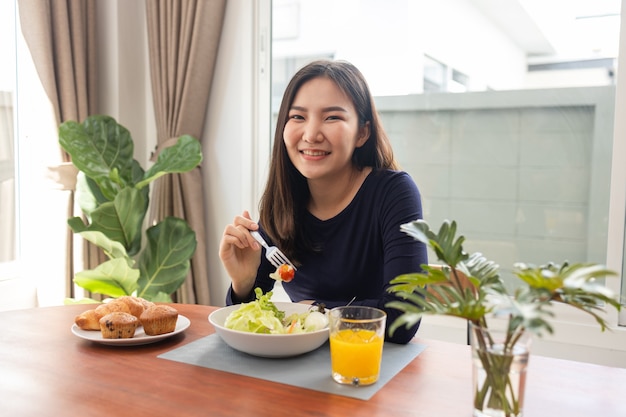 Essenskonzept eine hübsche Frau, die ein kalorienfreies Salatdressing mit einem grünen Salat mischt