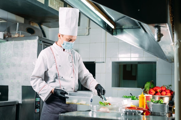 Foto essenslieferung im restaurant. der küchenchef bereitet im restaurant die speisen zu und verpackt sie in einweggeschirr.