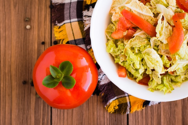 Essfertiger Gemüsesalat, Tomaten und Chinakohl auf einem Holztisch, Draufsicht