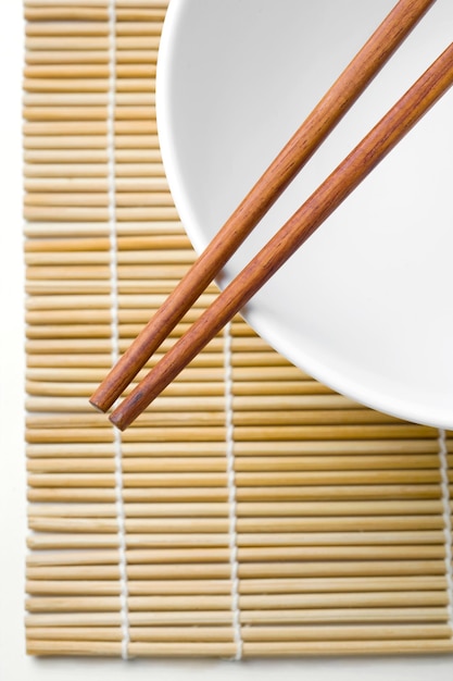 Essstäbchen aus Holz auf einer weißen Schüssel isoliert auf weißem Hintergrund