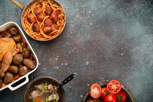 Esstisch mit traditionellen leckeren hausgemachten Gerichten: Hühnersuppe, Frikadellen-Spaghetti, gebratenes Huhn mit Kartoffeln. Klassisches, natürliches Komfortessen für Familienessen, Draufsicht, Kopierraum