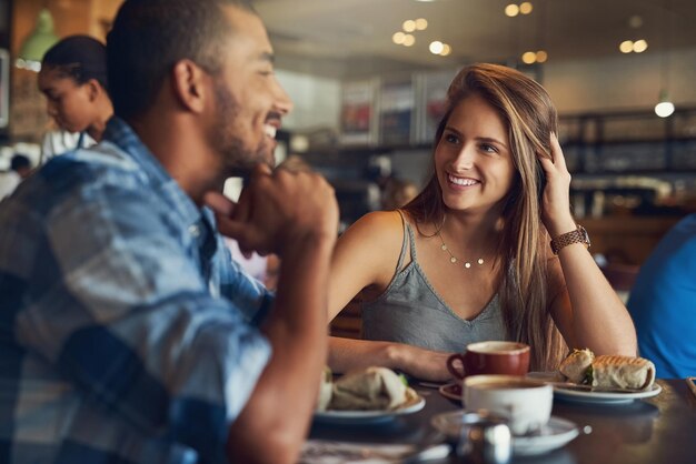 Se está convirtiendo en una primera cita impresionante Captura recortada de una pareja joven en una cita en un café