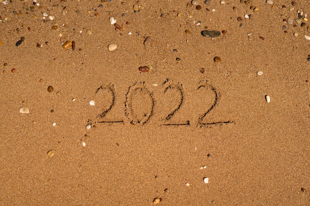 está desenhando na areia de uma praia com uma onda à beira-mar férias no mar conceito de ano novo