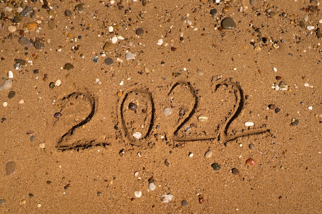 está dibujando en la arena de una playa con una ola junto al mar vacaciones en el mar concepto de año nuevo